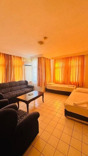 Een hotelkamer met een bank, een bed, een klein tafeltje en gordijnen.