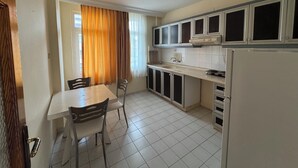 Een keuken met witte kastjes, een spoelbak en een eettafel met stoelen.