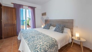 A bedroom with a large bed, a wooden door, and a view through a glass door to the outside. - Sa Copinya, Villa in front line of the beach, Mallorca (Son Servera)