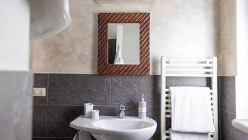 A bathroom with a white sink, a mirror with a wooden frame, a towel rack, and a bottle of hand soap.