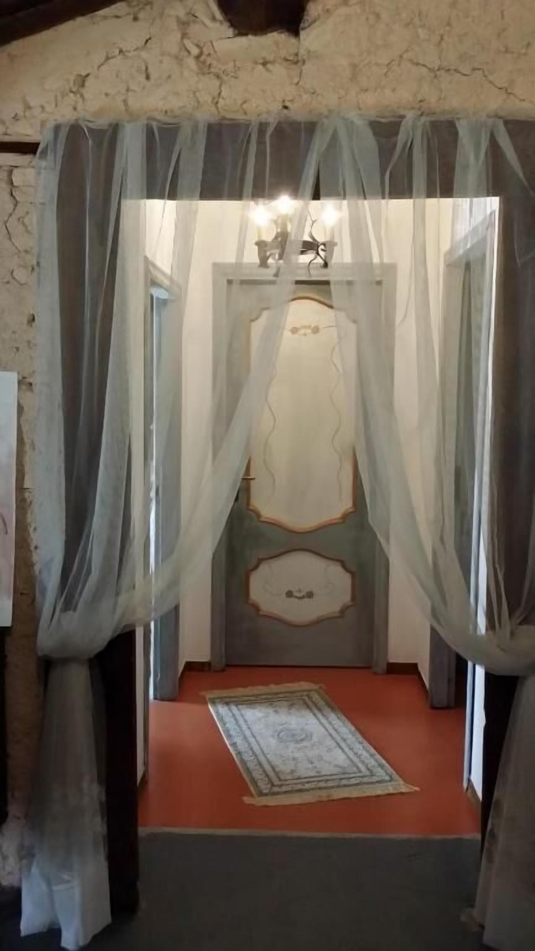 Una habitación con una cama bajo un dosel, un tapete y una pared con un panel decorativo.