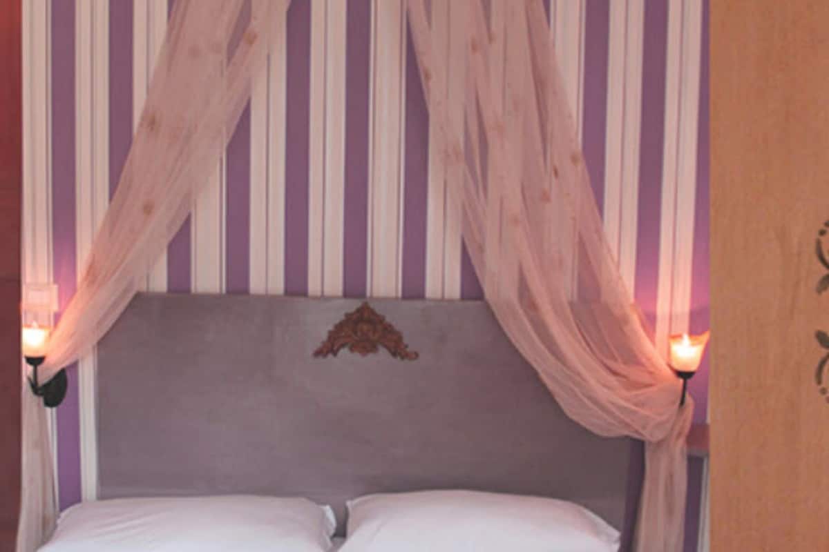 Un dormitorio con cama, papel tapiz a rayas y dosel.