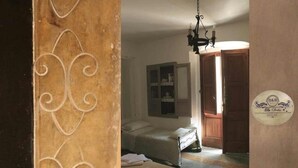 Une chambre avec deux lits, une porte en bois, un lustre et un meuble fixé au mur.