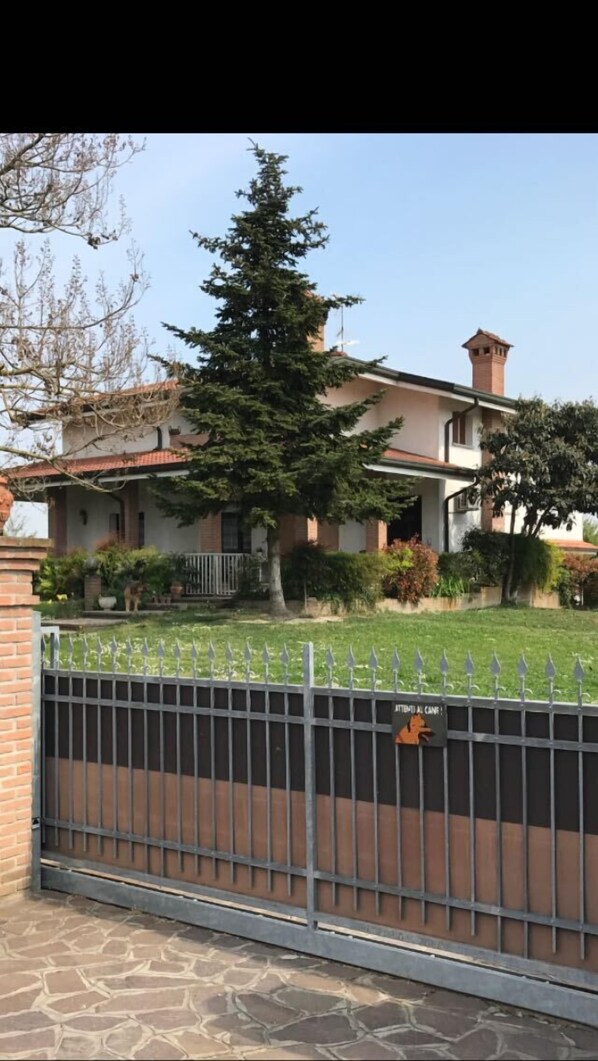 Una casa de dos pisos con fachada de ladrillo, una chimenea y un árbol grande en el frente.