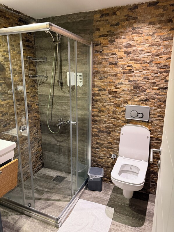 Un baño moderno con ducha de vidrio, inodoro y lavamanos.