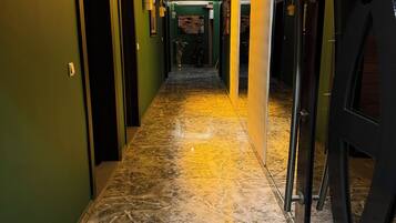 Un pasillo con paredes verdes, piso de mármol y una puerta con un letrero.