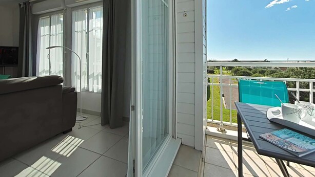 Un balcon avec vue sur la mer, un canapé et une table avec un magazine.