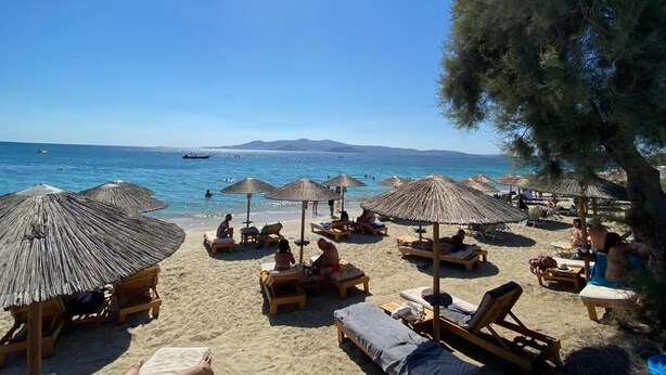 A beach with sun loungers and umbrellas, a clear sky, and the sea in the background. - Manios Suites (Naxos)
