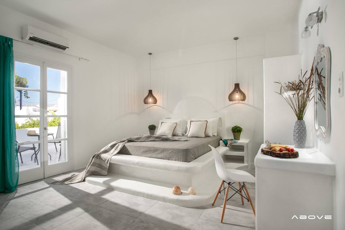 A modern bedroom with a bed, bedside tables, a chair, and a view of the outdoors.