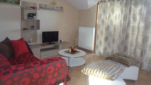 A room with a bed, a sofa, a TV, and a small table with a lamp. - Sea View Athina's Home (Kefalonia)
