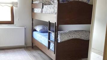 Une chambre avec un lit superposé, un radiateur, un tapis à motifs et une armoire.