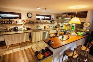 A kitchen with wooden flooring, a central island, and bar stools.