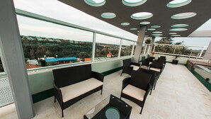 A rooftop terrace with wicker furniture, large windows, and a view of the surrounding landscape. - City Falls Iguazú (Puerto Iguazú)