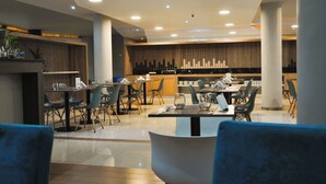 Un restaurante moderno con barra, varias mesas y sillas, y un diseño contemporáneo y limpio.