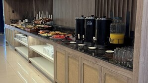 A buffet setup with a variety of food items, a coffee station, and a beverage dispenser. - City Falls Iguazú (Puerto Iguazú)