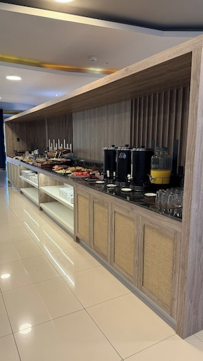 A buffet setup with a variety of food items, a coffee station, and a beverage dispenser.
