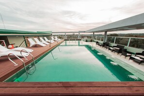 Una piscina al aire libre, sillones reclinables de piscina