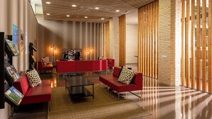 Um lobby moderno com sofás vermelhos, uma mesa de centro e painéis de madeira.
