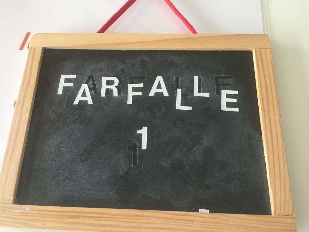 Una pizarra con la palabra "FARFALLE" y el número "1" escrito.