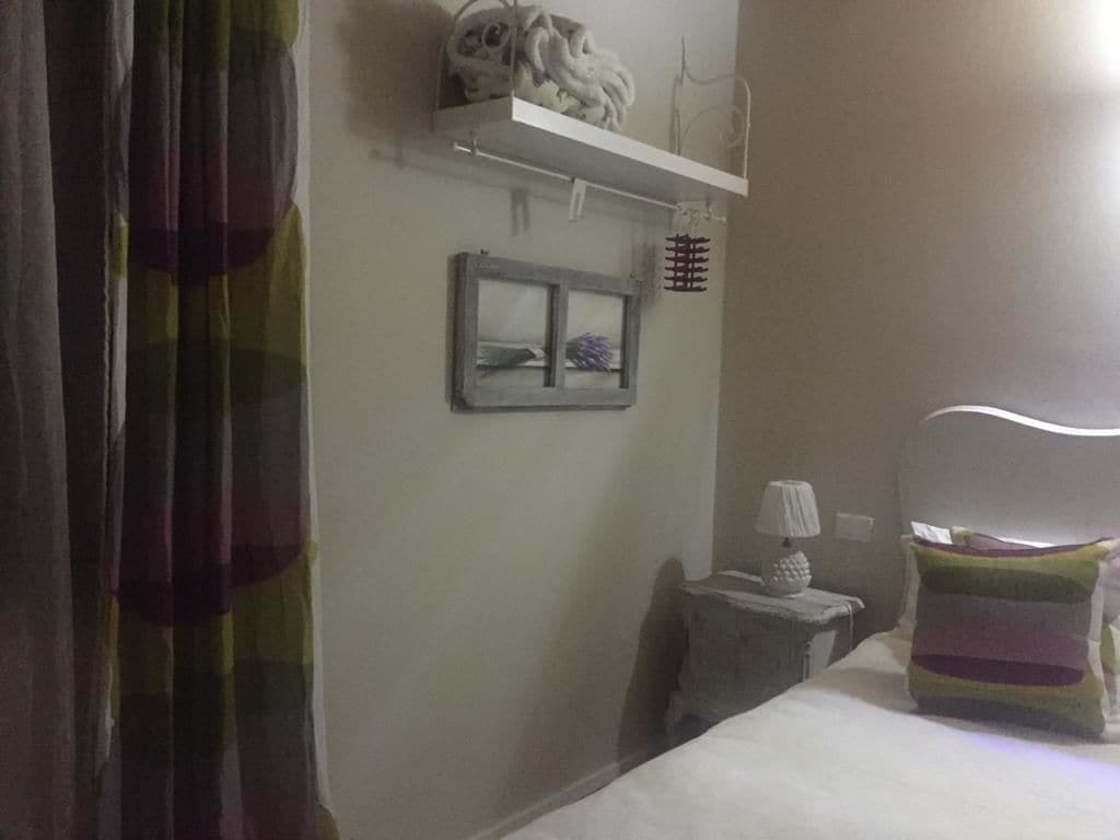 Ein Hotelzimmer mit Bett, Nachttisch, Lampe, einer Ablage mit Dekoration und einem Fenster mit Blick.