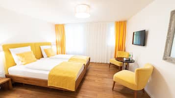 Ein Hotelzimmer mit Doppelbett, einem kleinen Tisch mit Stuhl und einem an der Wand montierten Fernseher.