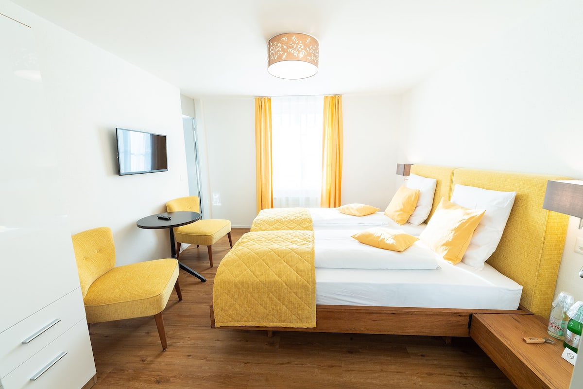 Una habitación de hotel con una cama, una silla, un escritorio y un televisor.