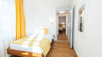 Ein Schlafzimmer mit einem hölzernen Bett, einer gelben Tagesdecke und einer weißen Wand.