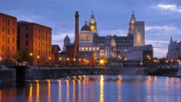 A historic cityscape with a prominent church and a river reflecting city lights.