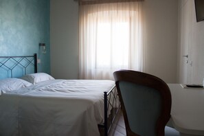 Een slaapkamer met twee bedden, een houten stoel, een nachtkastje en een raam met gordijnen.