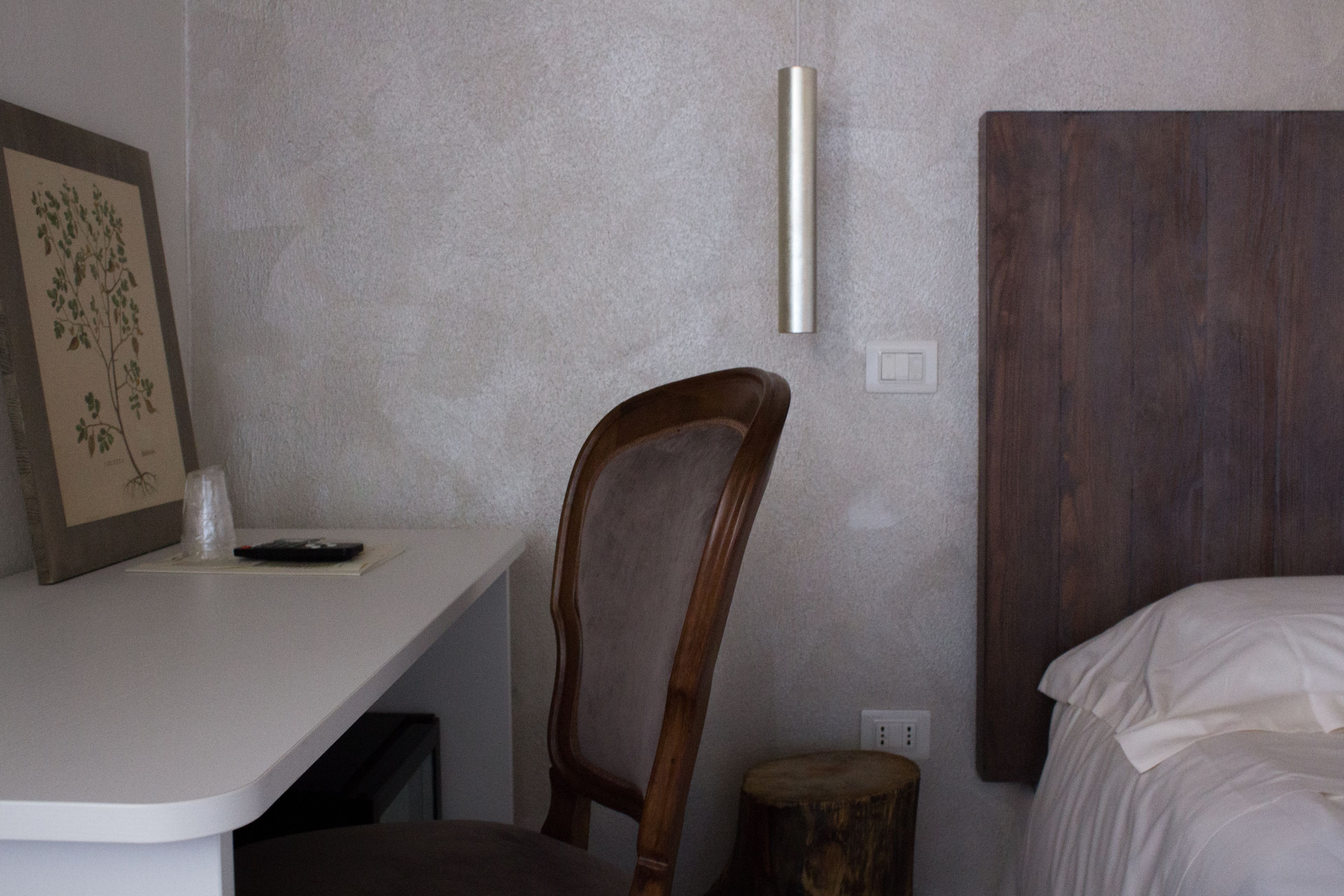A bedroom with a wooden headboard, a bedside table with a remote control, and a framed picture on the wall.