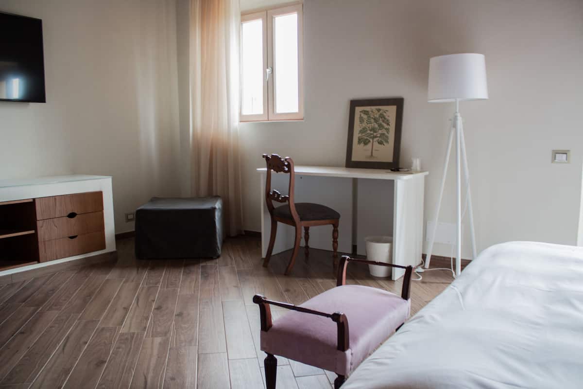 Une chambre d’hôtel avec un lit, un bureau et une chaise, un lampadaire et un téléviseur fixé au mur.