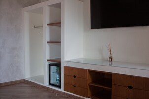 Una habitación moderna con televisor incorporado, armarios de madera y estante de vidrio.