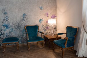 Una habitación con dos sillones de terciopelo azul, una mesita de madera y una lámpara.
