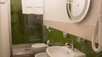 Une salle de bain avec une douche à parois de verre, deux toilettes, un lavabo et un miroir.