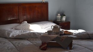 A neatly made bed with a starfish decoration, a bedside table with a lantern, a kettle, and a plate of pastries. - Country Hill B&B (Arezzo)