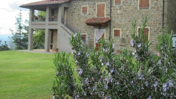A stone building with a red-tiled roof, a balcony, and a grassy lawn. - Country Hill B&B (Arezzo)