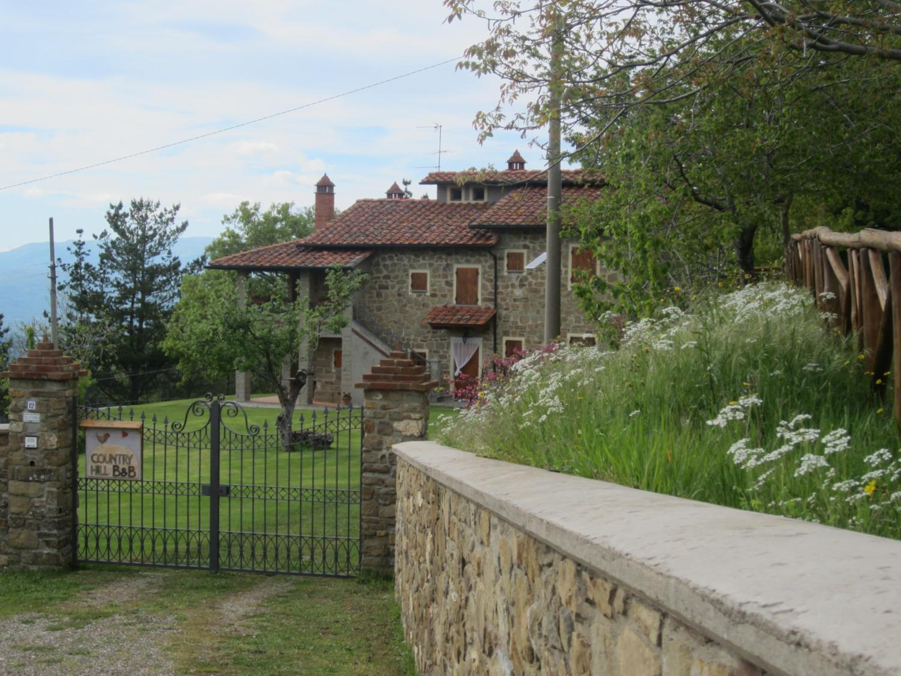 Un bâtiment en pierre avec un toit en tuiles, un portail en pierre et une enseigne indiquant « Country Hill B&B ».