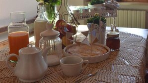 A table with a lace tablecloth, a teapot, cups, a vase with flowers, and a decorative stand with plants. - Country Hill B&B (Arezzo)