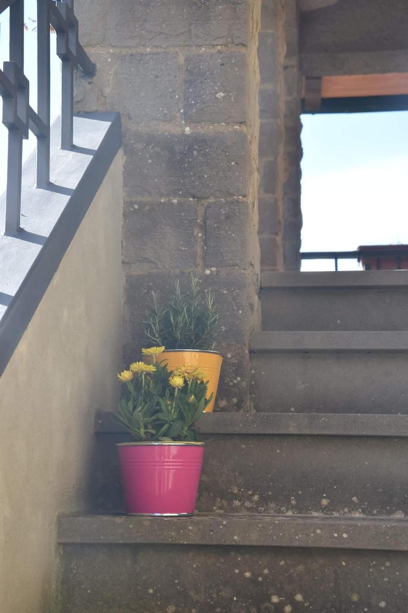 Una escalera con pared de piedra y barandilla de metal.