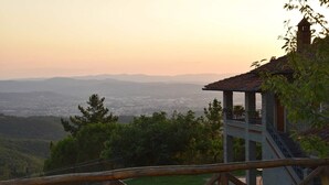 A gazebo with a stone base and a tiled roof overlooking a cityscape and distant mountains. - Country Hill B&B (Arezzo)
