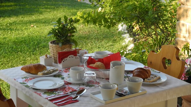 A table set outdoors with plates, cups, and a basket of bread. - B&B Mimosa e Lillà (Fumane)