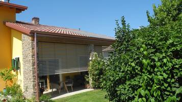 A house with a stone facade, a tiled roof, and a covered patio area with outdoor furniture.