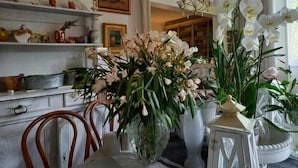 A dining area with a white table, chairs, and a vase of flowers. There is a mirror above the table and a chandelier in the background. - Blue Lodge in Bordeaux (Bordeaux)