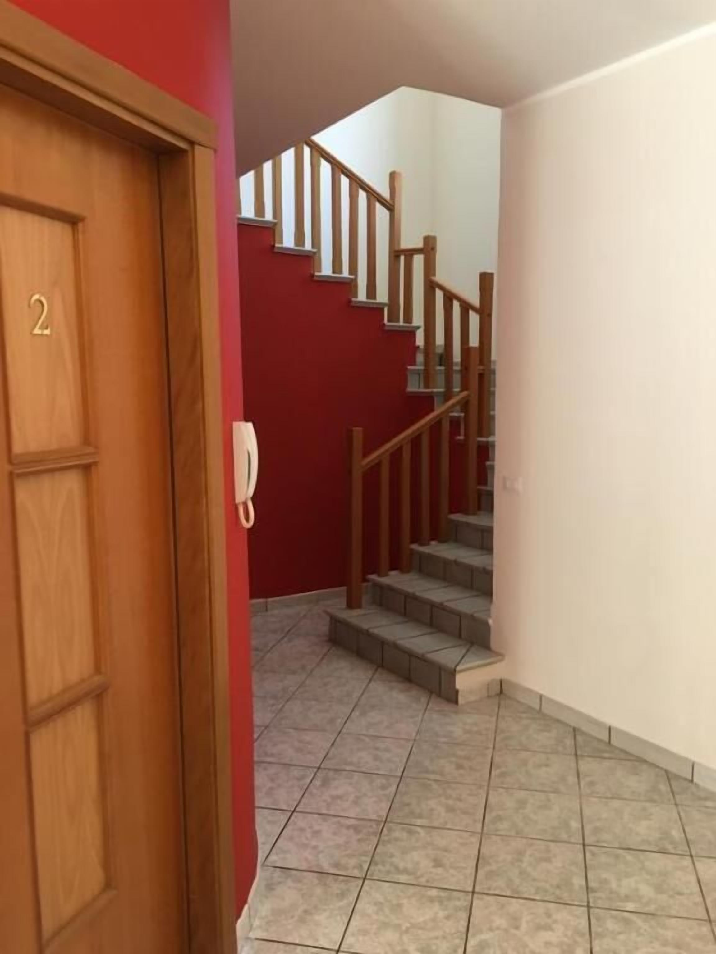 A staircase with wooden railings and a red wall.