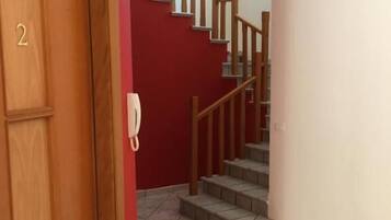 A staircase with wooden railings and a red wall.