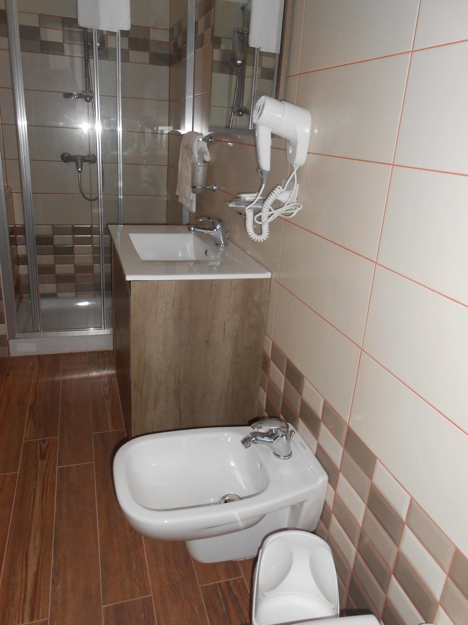 Un baño con ducha, lavamanos y bidé.