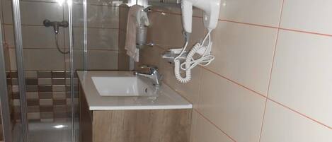 A bathroom with a shower, a sink, and a bidet.