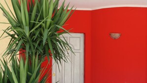 A red and yellow building facade with a door and a potted plant in the foreground. - B&B Paradiso (Falerna)