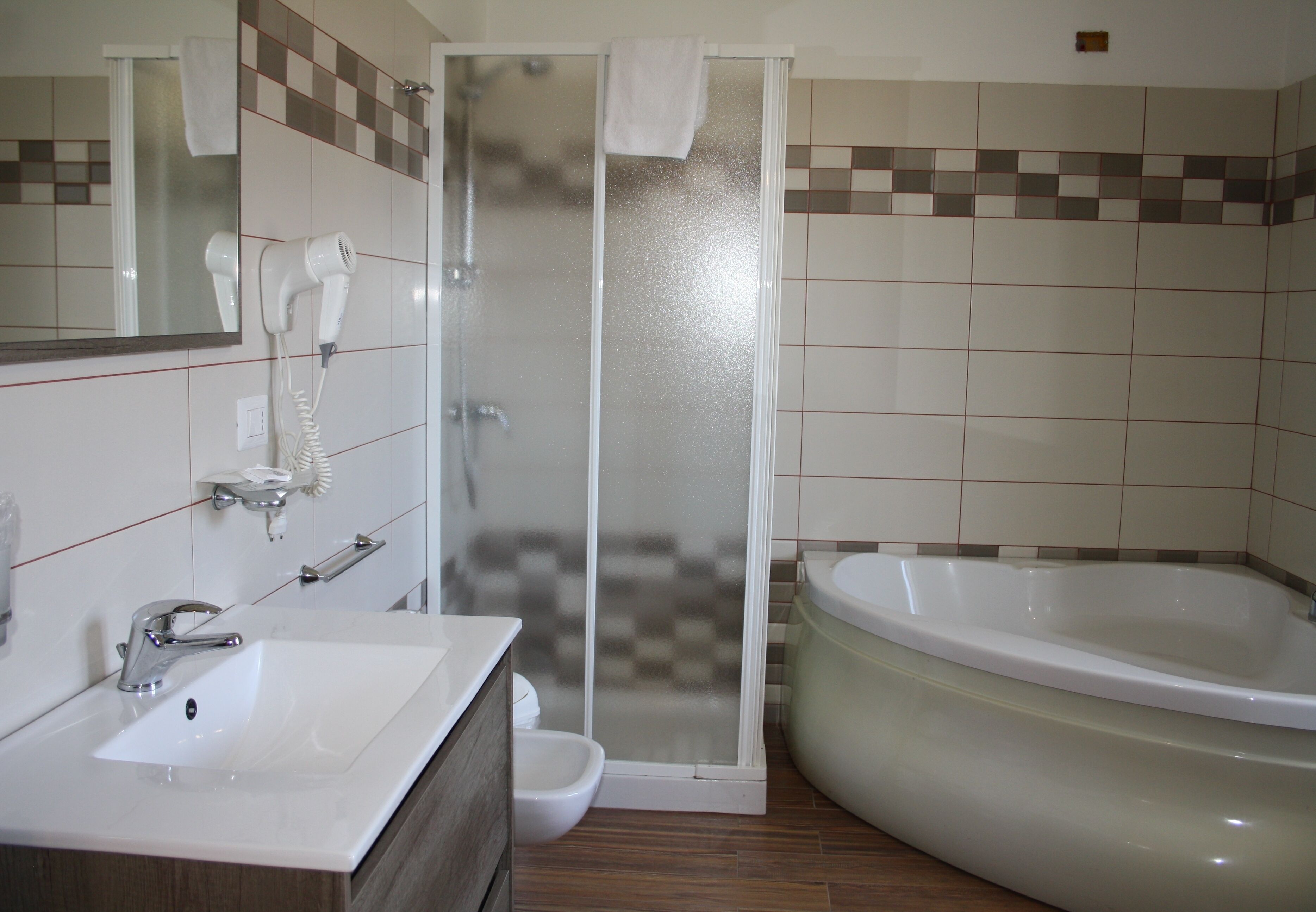 A bathroom with a sink, a hairdryer, a shower, and a bathtub.