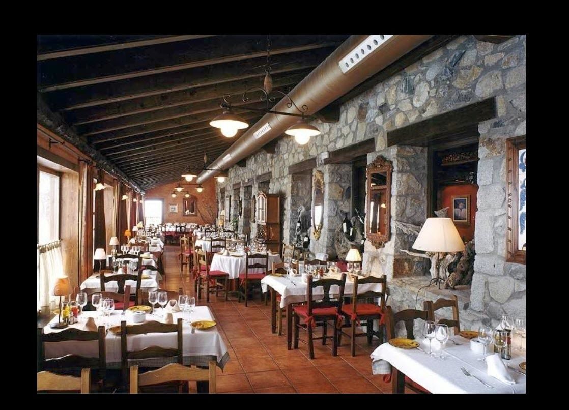 A restaurant with stone walls, wooden beams, and tables set for dining.